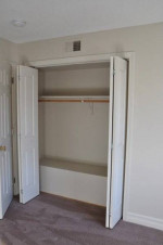 Spacious closet with double doors in Stone Farm Apartments, Lebanon, NH, featuring carpeted flooring.