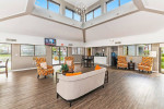 Spacious and modern community lounge at Palms at Sand Lake apartments with bright seating and large windows.