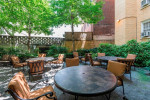 Outdoor courtyard of Miramar apartments in Washington with tables and chairs surrounded by greenery.