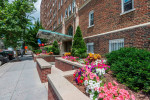 Entrance of Miramar Apartments in Washington, featuring flower beds and modern architecture.
