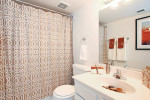 Modern bathroom featuring stylish shower curtain, sleek sink, and decorative towels in a renovated apartment.