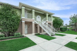 Exterior view of a two-bedroom apartment building at Harvard Condominiums in Melbourne, Florida, featuring green accents.