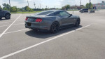2015 Ford Mustang GT in parking lot, featuring low miles and supercharger, ready for sale.