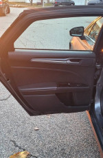 Interior view of the 2013 Ford Fusion Titanium AWD driver's door with controls and leather finish.