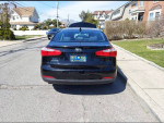 Black Kia Forte parked on a street, showcasing low mileage and good condition.