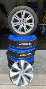 2020 Tesla Model S wheels with Michelin tires stacked with tire covers in a garage
