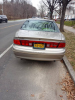 Rear view of a 2001 Buick Century, a reliable used car needing some repairs, with a New York license plate.