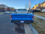 Rear view of a 1977 Ford F150 4x4 Pickup truck in vibrant blue color, parked in a residential area.