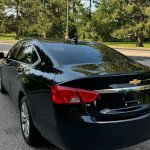 Black Chevrolet Impala with privacy tint and sleek design, parked in a lush green area.