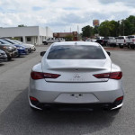 Rear view of a silver INFINITI Q60 Coupe parked in a dealership lot with other cars.