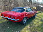 1970 Pontiac Firebird convertible parked in a grassy area, showcasing its striking red color and classic design.