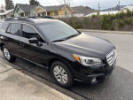 2017 Subaru Outback 2.5i AWD in black, parked on street, showcasing its clean design and all-weather capability.