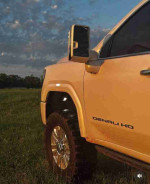 Close-up of a 2006 GMC Sierra 1500HD SLT pickup truck showing its powerful design and rugged tires in a field.