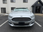 Front view of a silver 2013 Ford Fusion SE sedan parked outside, showcasing clean exterior and modern design.