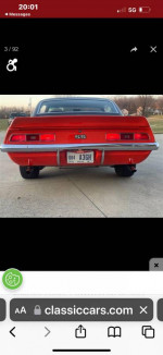 1969 Chevrolet Camaro SS in Hugger orange, showcasing rear view with black stripes and emblem.