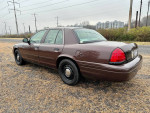 2008 Ford Crown Victoria P71 Police Interceptor parked on a gravel road with a view of buildings in the background.