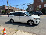 2016 Kia Sedona L minivan with backup camera parked on the street, showcasing its clean exterior and spacious design.