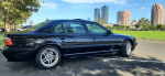 2001 BMW 740iL RWD parked outdoors, showcasing a sleek black exterior and city skyline backdrop.