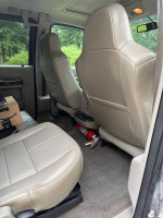 Interior view of a 2010 Ford F350, showcasing beige seats and fire extinguisher in the back.