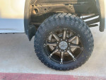 Close-up of a 2018 GMC Sierra 2500HD truck wheel with off-road tire and black alloy rim.