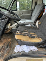 Interior of a 1993 Chevy Tiltmaster Van showing worn seats and driver area, suitable for cargo transport.