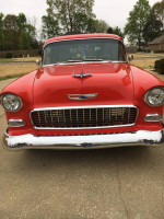 Front view of a restored 1955 Chevy Sedan Delivery in bright red with chrome detailing.
