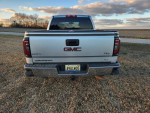 Rear view of a GMC Sierra 1500 pickup truck, featuring a silver body and black leather interior.