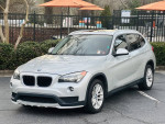 2015 BMW X1 xDrive28i AWD in silver parked, showcasing clean exterior and stylish design.