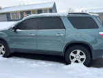 2009 GMC Acadia SUV parked in snow, featuring tinted windows and snow on the roof