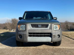 Front view of a clean, green 2003 Honda Element parked on a driveway under a clear blue sky