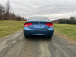 Rear view of a blue 2008 Honda Civic LX parked on a grass field, showcasing its clean design.