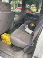 Interior view of a 2002 Ford F-150 quad cab with gray upholstery and miscellaneous items in the back seat.