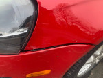 Close-up of the front fender of a red VW Jetta with visible scratches and dings.