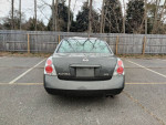 Rear view of a gray Nissan Altima, showcasing clean lines and no visible damage, parked in a lot.