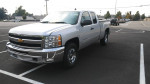 2012 Chevrolet Silverado 1500 LT 4WD in silver, featuring extended cab and chrome wheels, parked in a lot