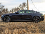 2014 Tesla Model S P85 in black, parked on grass, showcasing sleek design and rear-wheel drive performance.