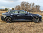 Side view of a 2014 Tesla Model S P85 with performance package parked on grass.