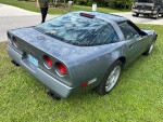 1990 Chevrolet Corvette in Steel Blue Metallic, well-maintained with 142672 miles, parked on grass.