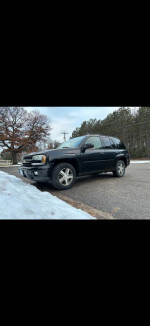 2005 Chevrolet Blazer in black parked on a snow-covered street, showcasing its rugged design and features.