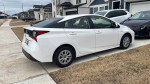 2021 Toyota Prius parked on the driveway, showcasing its hybrid technology and sleek design.