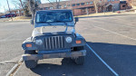 Front view of a 2002 Jeep Wrangler for sale, showcasing its rugged design in a parking lot.