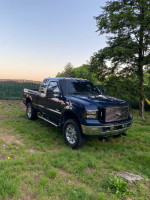 2006 Ford F350 Lariat 4WD truck with blue exterior parked on grass, showing minor rust.
