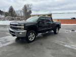 2015 Chevrolet Silverado 1500 LTZ 4WD parked in a snowy area, showcasing its shiny black exterior and chrome details.