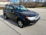 2013 Subaru Forester parked on a paved area, showcasing its dark exterior and well-maintained condition.