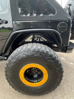 Close-up of a black Jeep Rubicon with off-road tires and custom yellow accents.