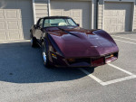 Gorgeous 1980 Chevrolet Corvette with burgundy metallic paint parked in front of garages.