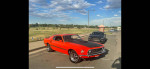 1969 Ford Mustang Mach 1 in Calypso Coral, parked outdoors with a black Mustang nearby.