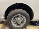 Close-up of the wheel and chassis of a partially restored 1960 Jaguar MK2 in a garage setting