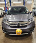 Front view of a 2019 Honda Pilot Touring in blueish-grey, showcasing its sleek design and polished appearance.
