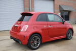 2015 FIAT 500 Abarth in red, featuring sporty design and unique rims, parked in front of a garage.